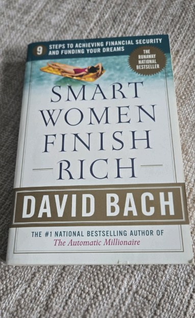 A copy of the book Smart Women Finish Rich by David Bach resting on a carpet