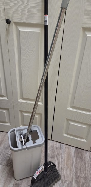 A mop and bucket set standing against a door