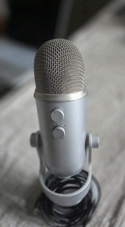 A silver microphone sitting on a wooden surface